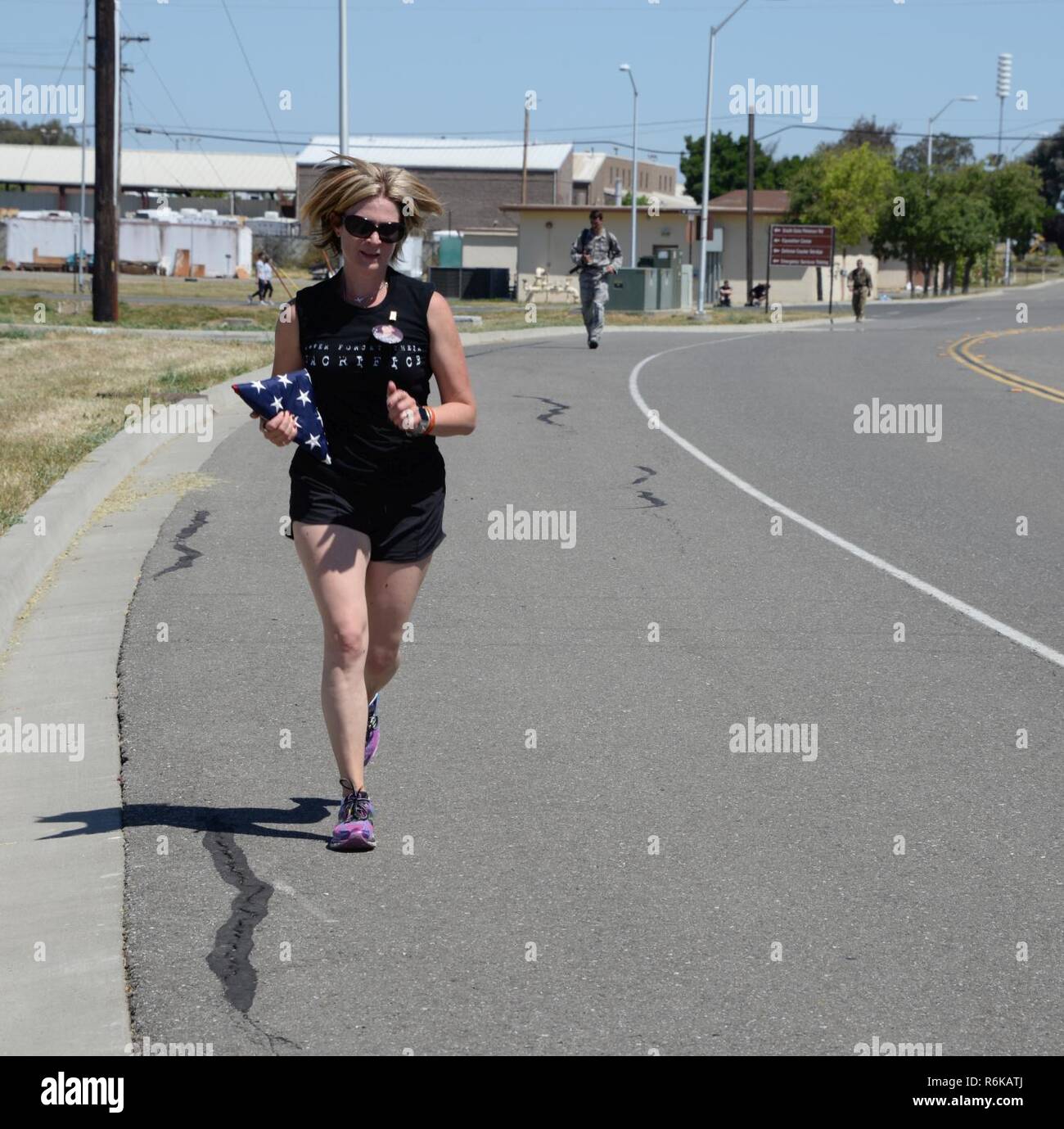 A Gold Star mother carries the American flag to honor her son as she nears the finish line of the 7th Annual Gold Star Families Ruck March at Travis Air Force Base, Calif., May 20, 2017. The event featured 275 participants and is held every year by the Travis First Sergeant's Council to support Gold Star Families. Stock Photo