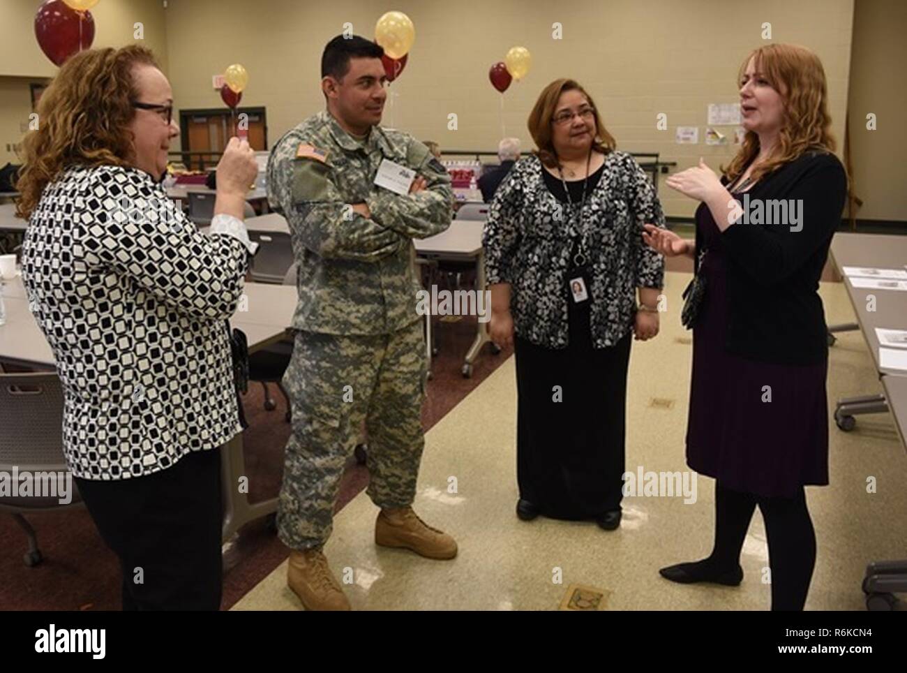 (From left to right) Mary Loss, a reading coach at Abraham Lincoln Elementary School, in Cicero, Ill, Army Sgt. Edgar A. Valdez-De Leon, a public affairs specialist, assigned to the 220th Public Affairs Detachment, Southfield, Mich., Marilyn Morales, and Philena Pugh, career day event coordinators for the Abraham Lincoln Elementary School, in Cicero, Ill. discuss the overall experience of the event May 5, 2017. Pugh and Morales both agree to invite Valdez-De Leon to the next annual career day to further share his success in the Army Reserve. Stock Photo