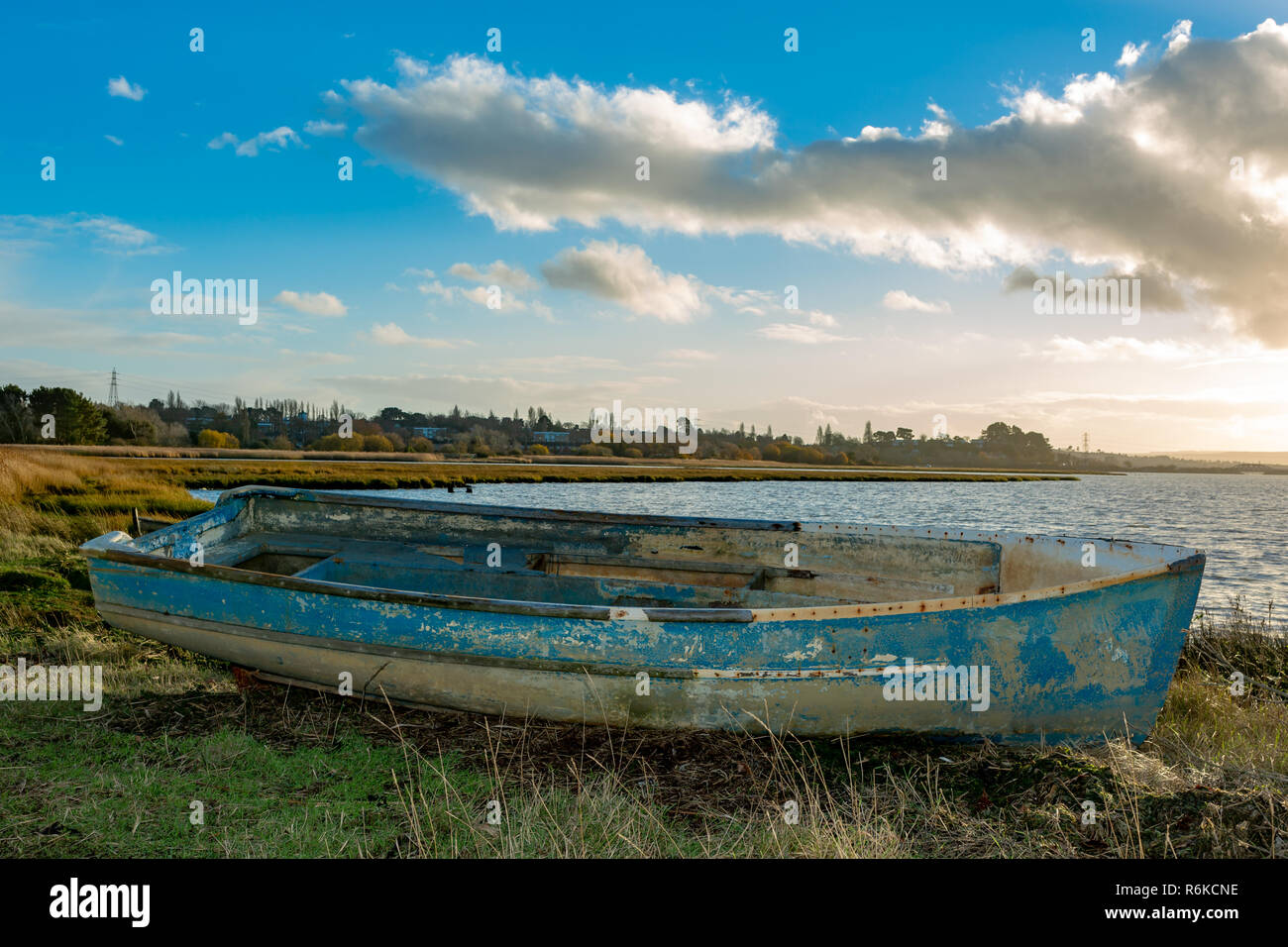 Landscape photograph of a wetland foreshore under a dramatic sky with derelict wooden boat in foreground. Stock Photo