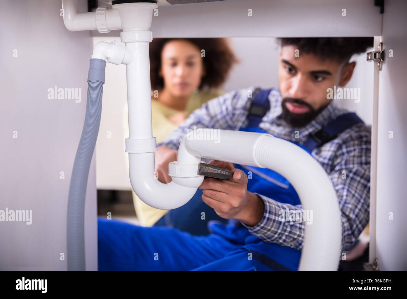 Woman fixing plumbing under sink hi-res stock photography and images
