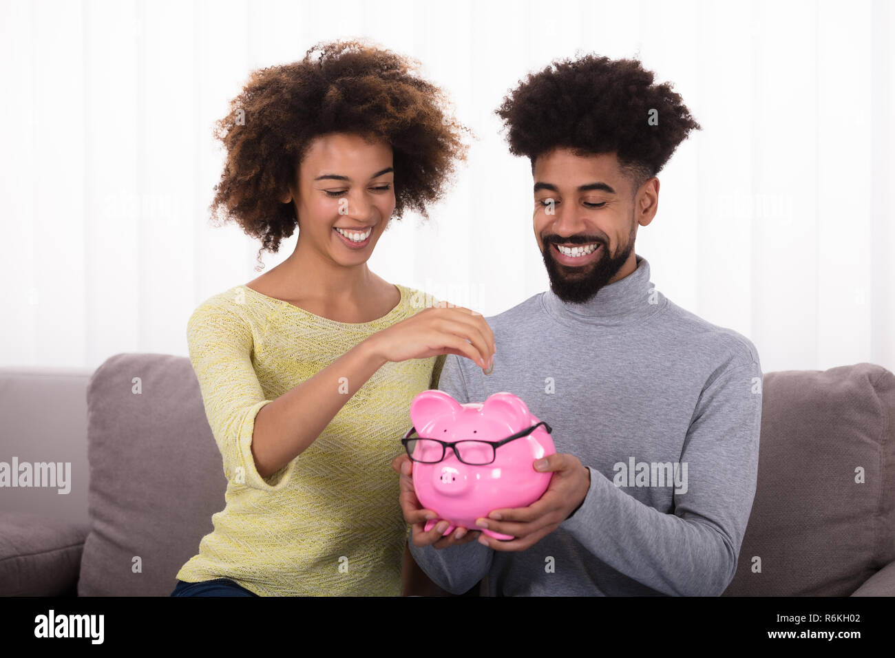 Couple Inserting Coin In Piggybank Stock Photo - Alamy