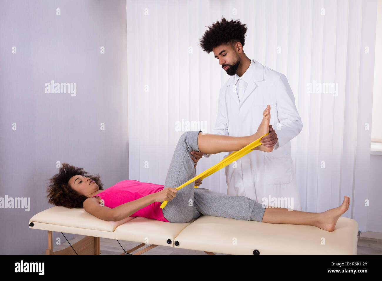 Physiotherapist Helping Patient While Stretching Her Leg Stock Photo