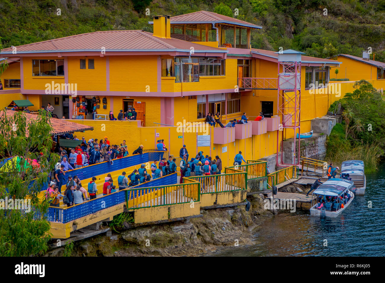 CUICOCHA, ECUADOR, NOVEMBER 06, 2018: Above view of yellow information building with some tourists boarding a boat to have a tour in the Cuicocha lake Stock Photo