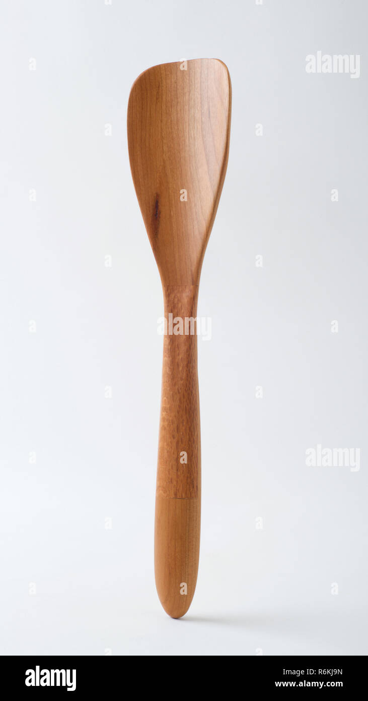 Handmade wooden spatula standing vertically on a white background. This