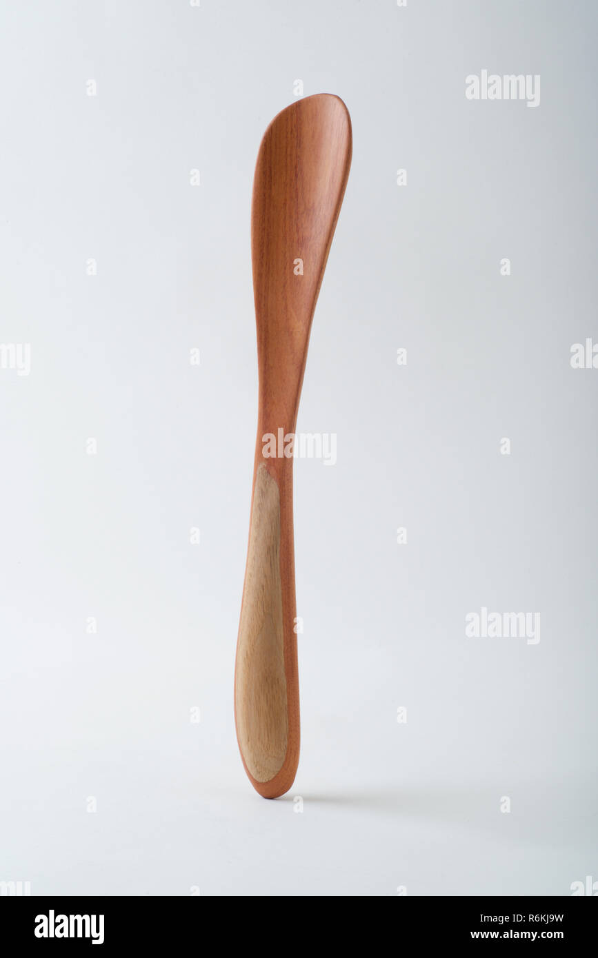 Handmade wooden spatula standing vertically on a white background. This