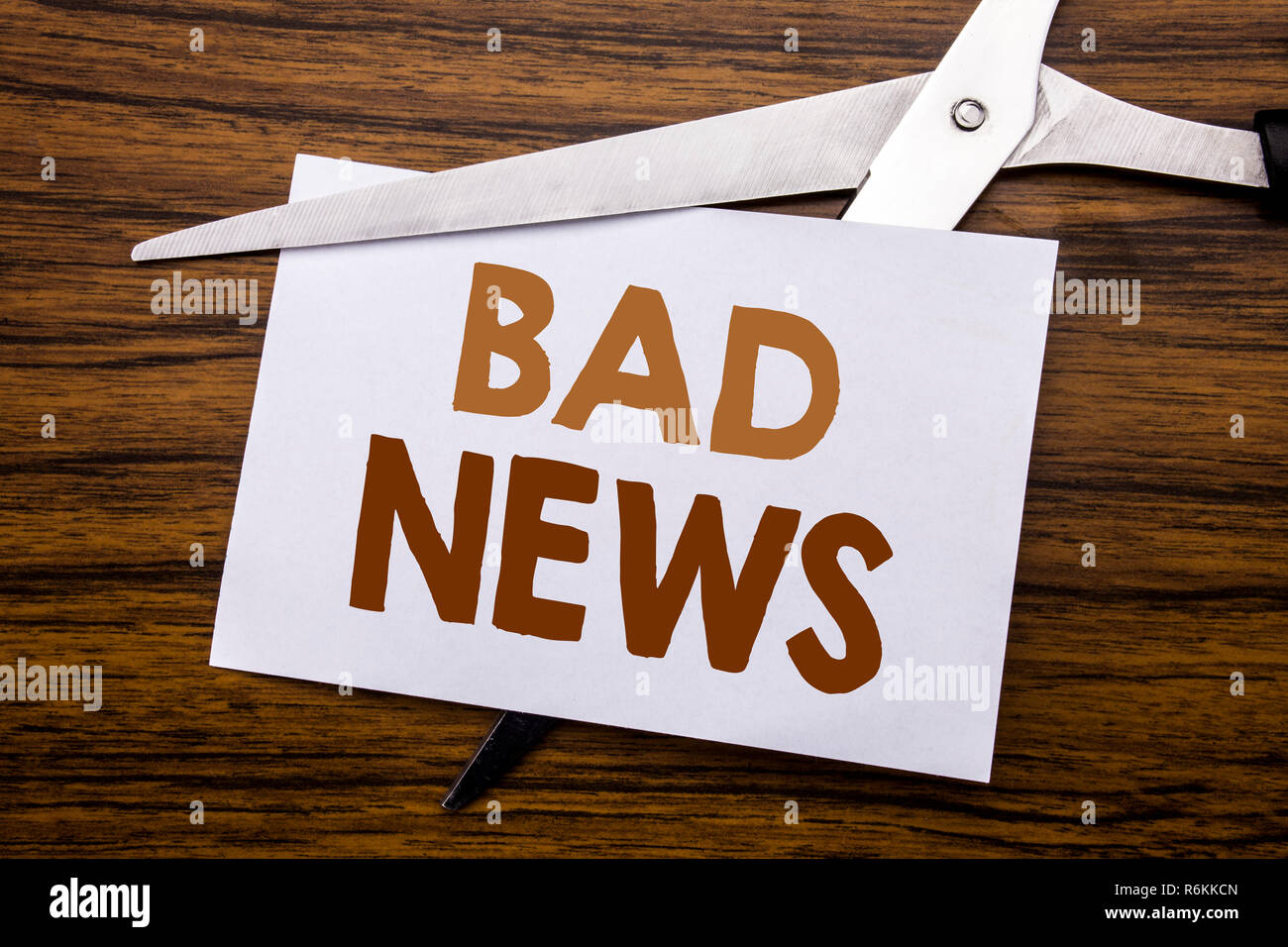Hand writing text caption inspiration showing Bad News. Business concept for Failure Media Newspaper Written on note, wooden back with colourful scissors meaning destroy stop of something. Stock Photo