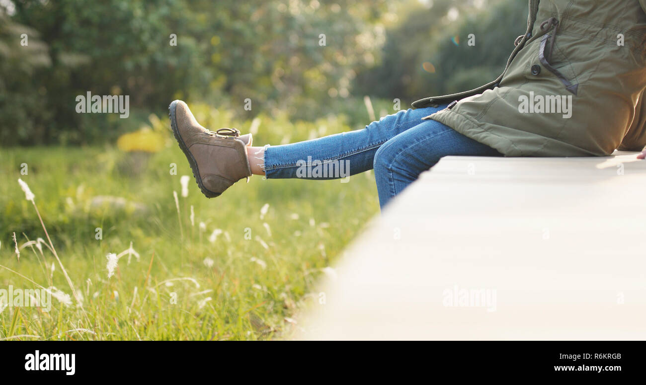 Woman sitting on the wooden edge of a wooden jetty and swing the legs ...