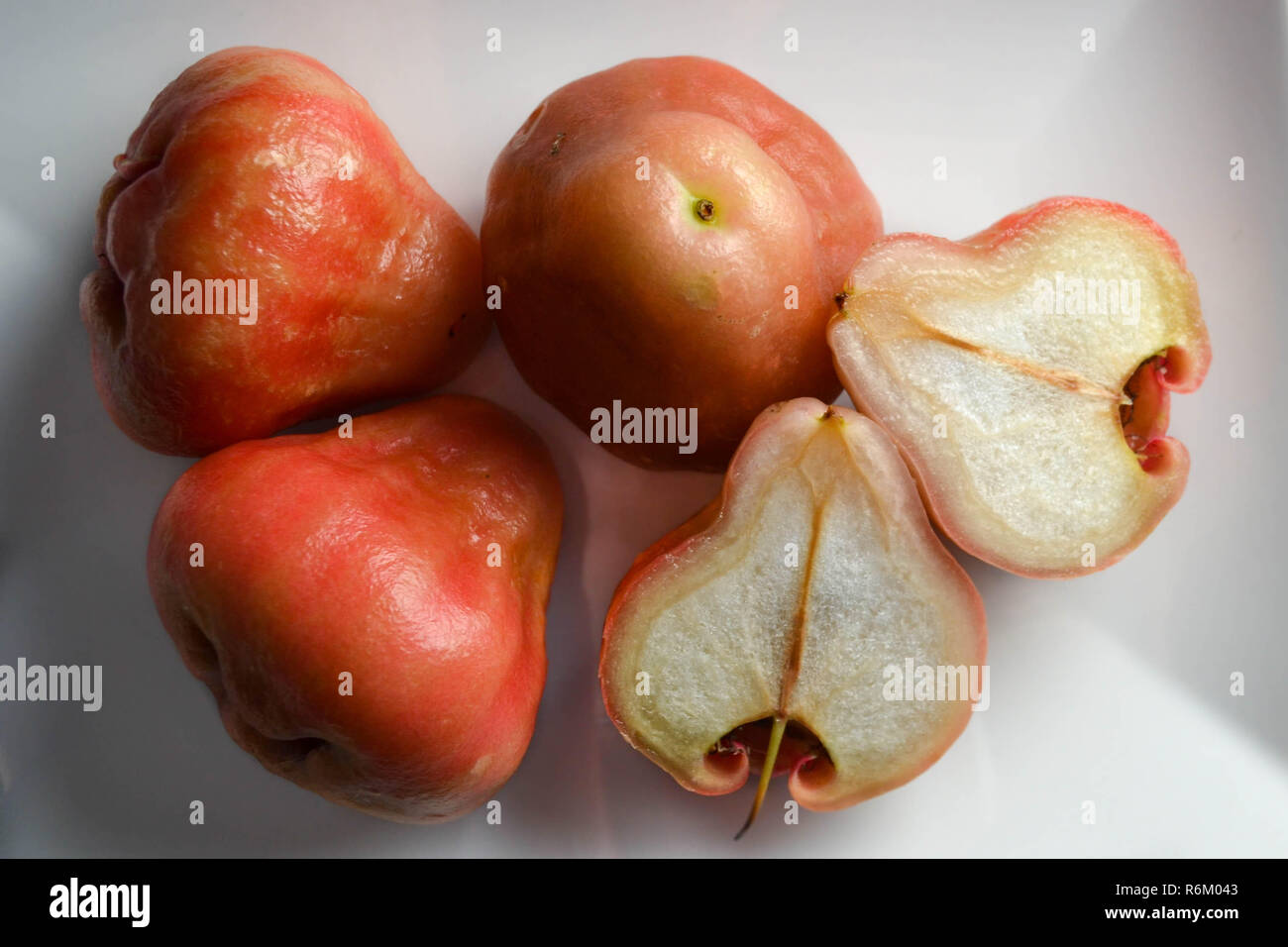 Wax Apples (aka Rose Apples - Syzygium samarangense) on a white plate, including one show in cross-section. Stock Photo