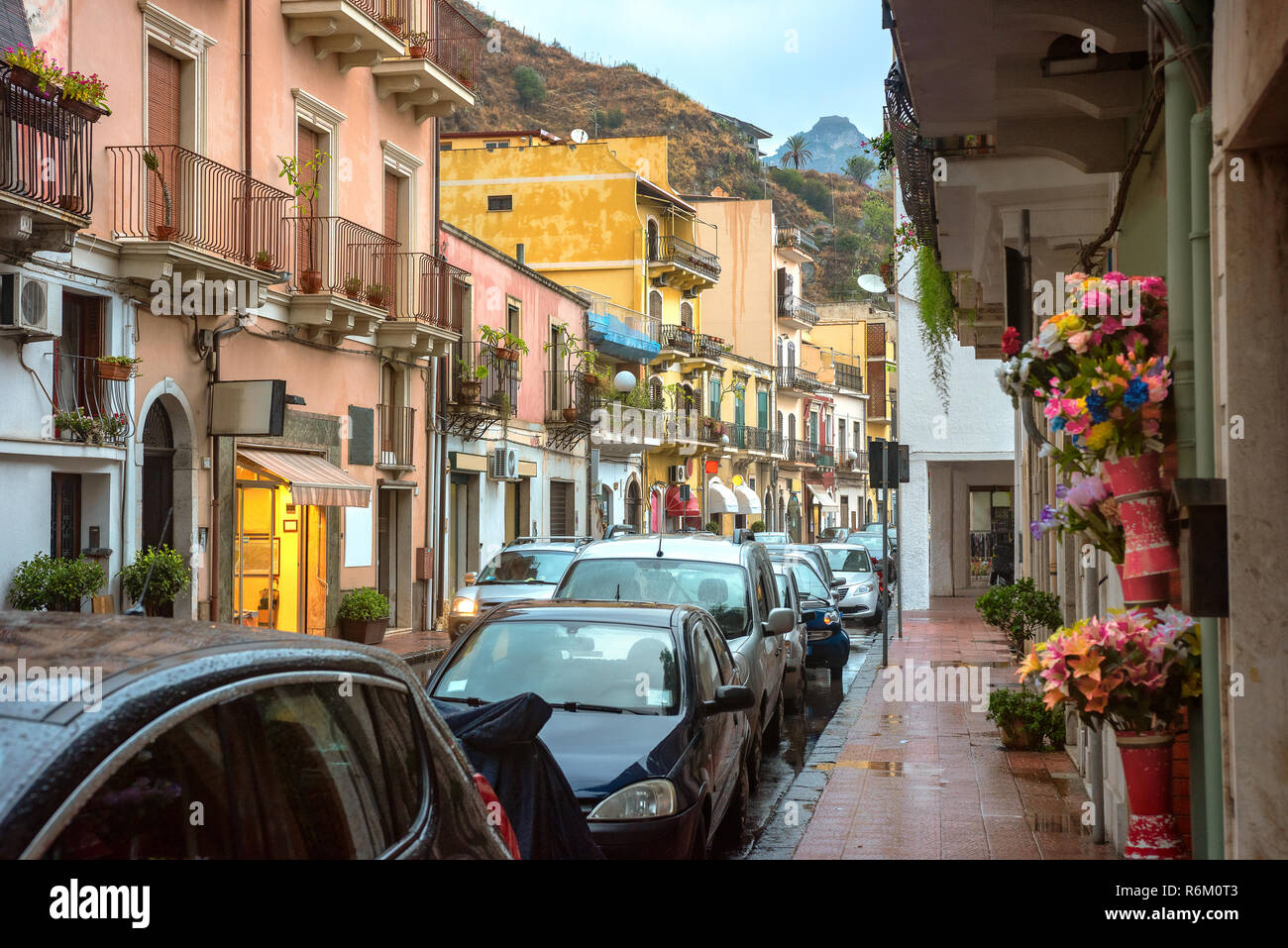 Cityscape with scenic apartment houses and pedestrian street at rainy twilight in Giardini Naxos near Taormina. Sicily, Italy Stock Photo