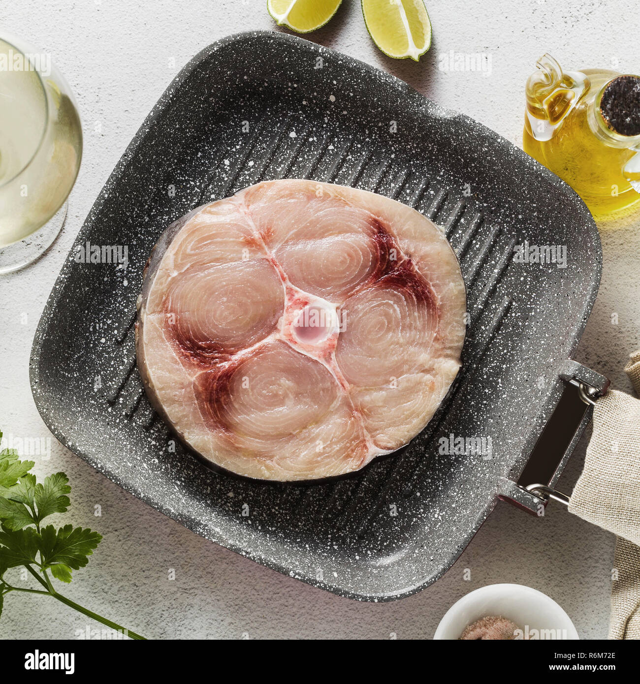 raw swordfish steak on the grill pan with olive oil and spices, white