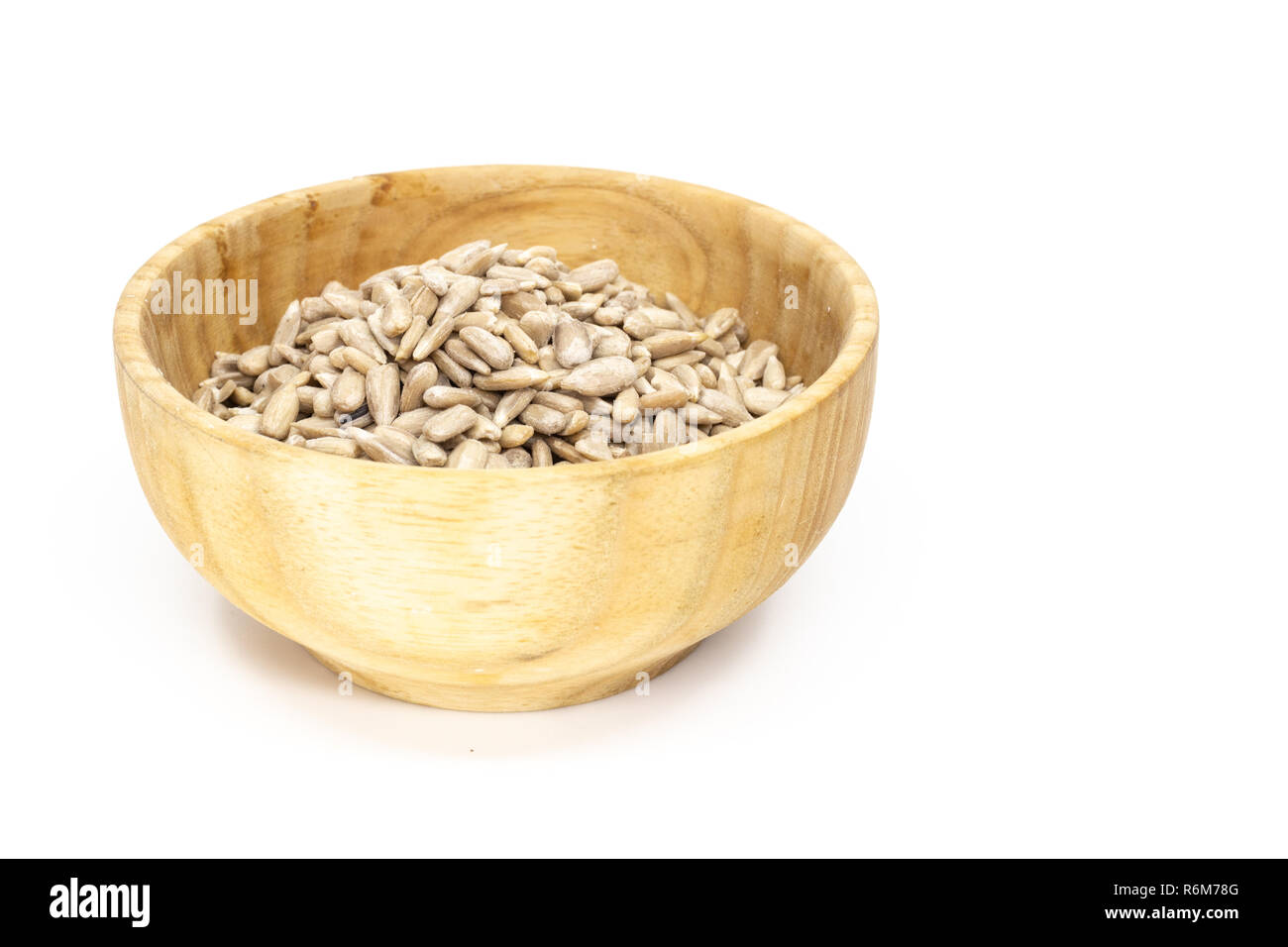 Sunflower seed dehulled kernel (Helianthus annuus) in wooden saucer, isolated on white Stock Photo