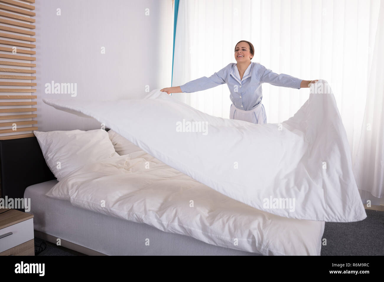 Housekeeper Arranging Bedsheet On Bed Stock Photo Alamy