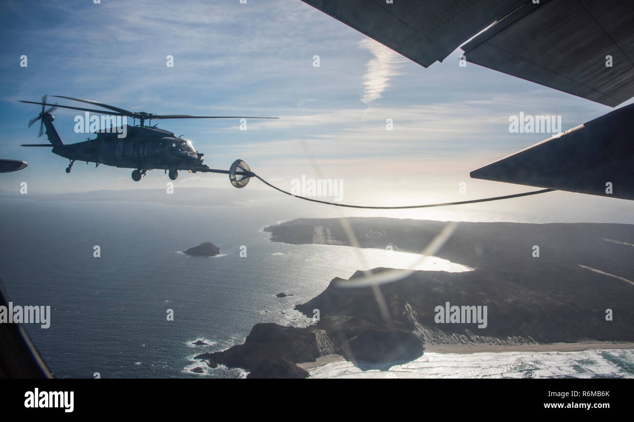 A U.S. Air Force HC-130J Combat King II aircraft refuels an HH-60 Pave Hawk helicopter  during a medevac mission over the Pacific Ocean Dec. 1, 2018. Pararescuemen aboard the HH-60 were assigned the job of recovering a civilian on a tanker and transporting them to a hospital. (U.S. Air Force photo by Airman Frankie D. Moore) Stock Photo