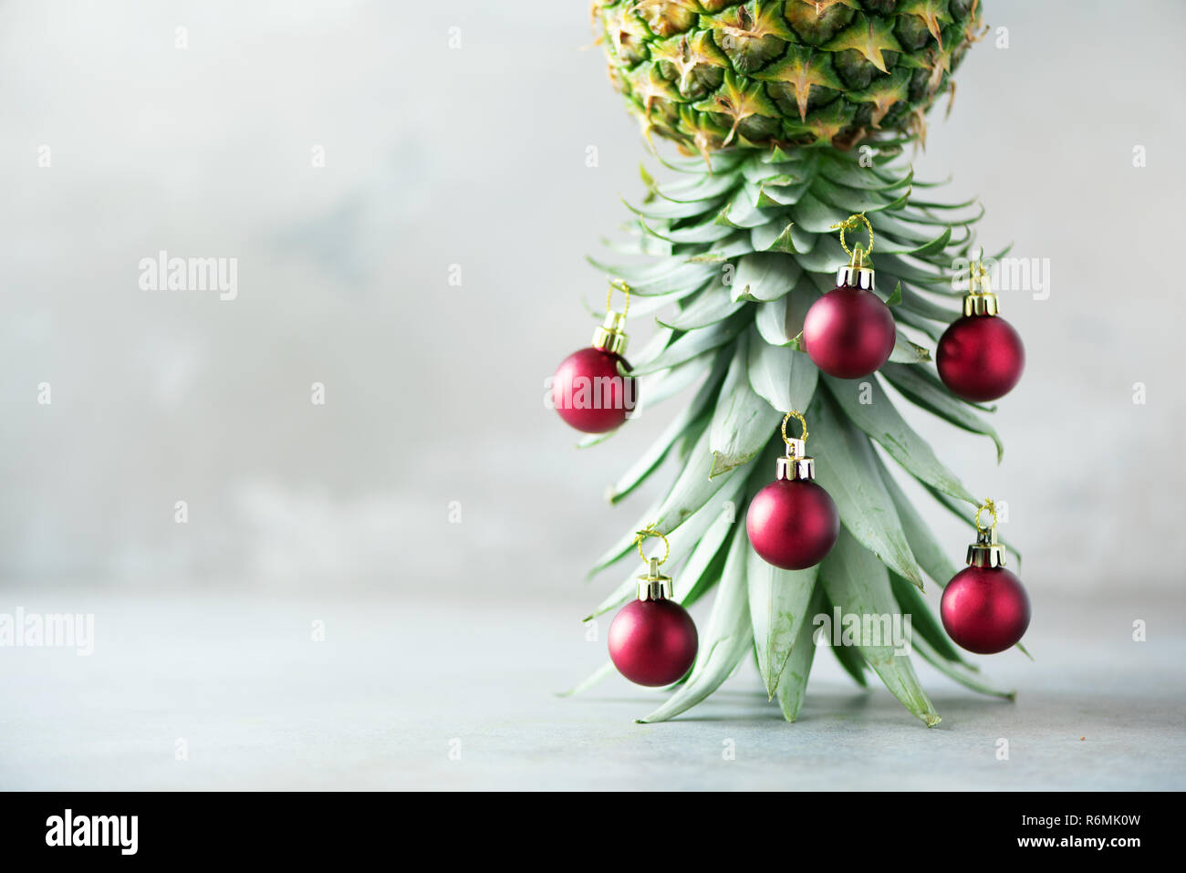 Creative Christmas Tree Made Of Pineapple And Red Bauble On Grey