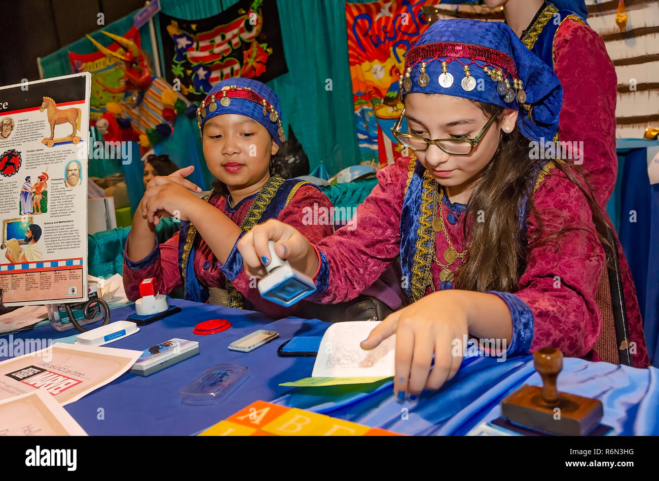 A girl dressed in traditional Puerto Rican clothing stamps a mock passport at the Mobile International Festival, Nov. 17, 2018, in Mobile, Alabama. Stock Photo