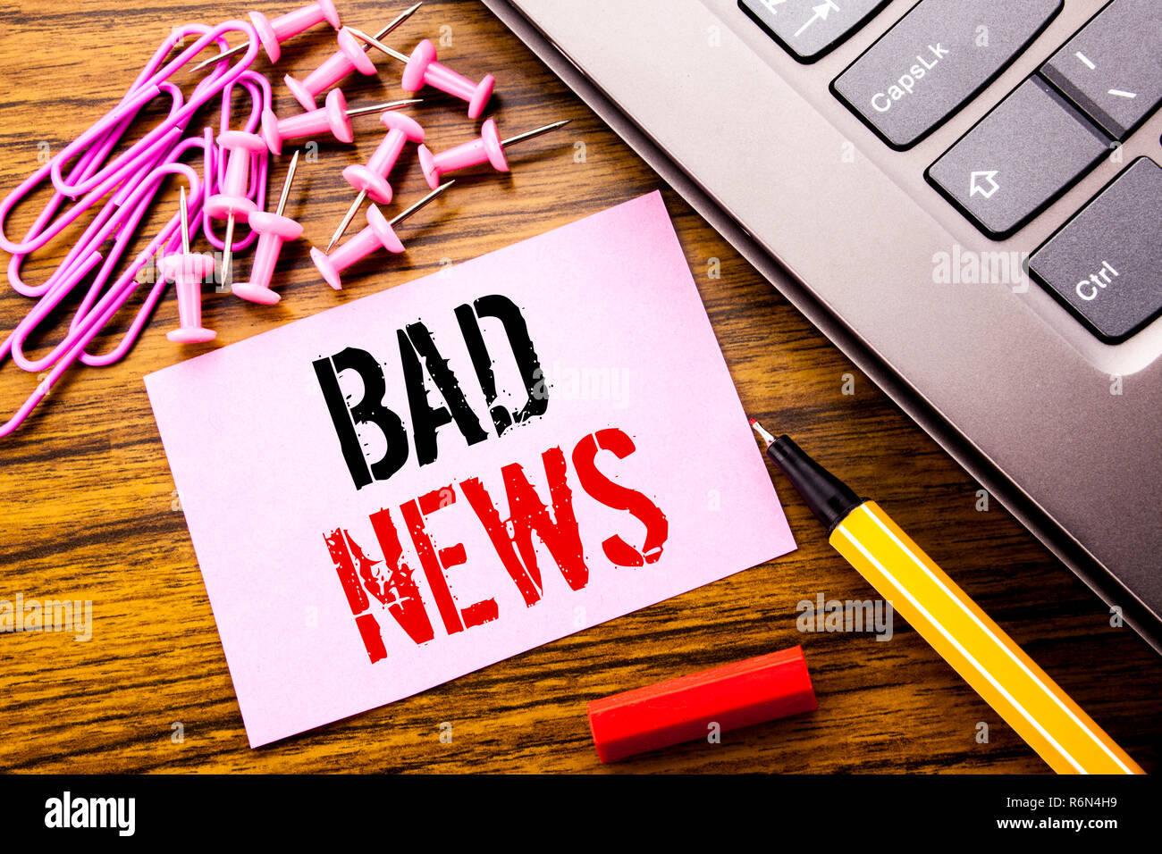 Handwritten text showing Bad News. Business concept for Failure Media Newspaper written on pink sticky note paper on the wooden background next to keyboard. With red pen. Stock Photo