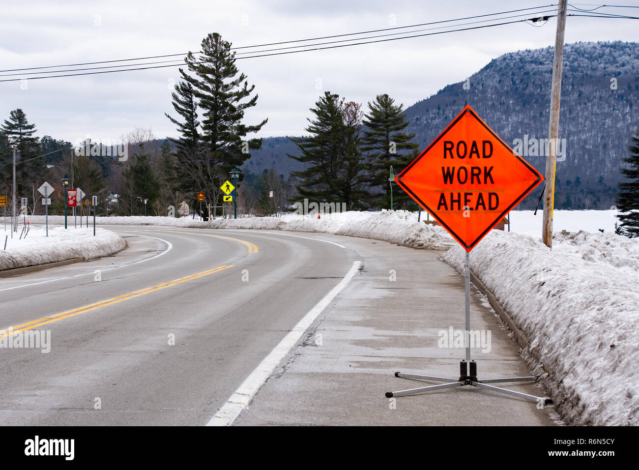 A road work ahead sign in snow covered Speculator, NY USA Stock Photo