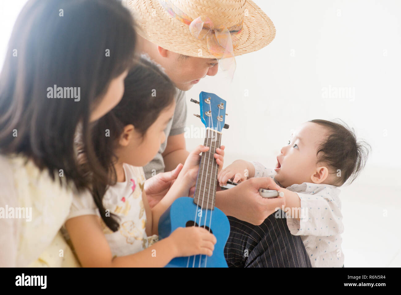 Asian family playing ukulele and harmonica at home Stock Photo Alamy