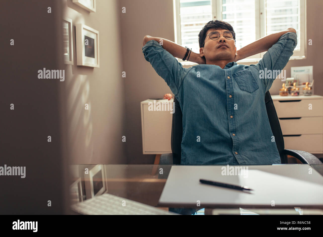 Businessman relaxing on chair leaning backwards with hands behind his