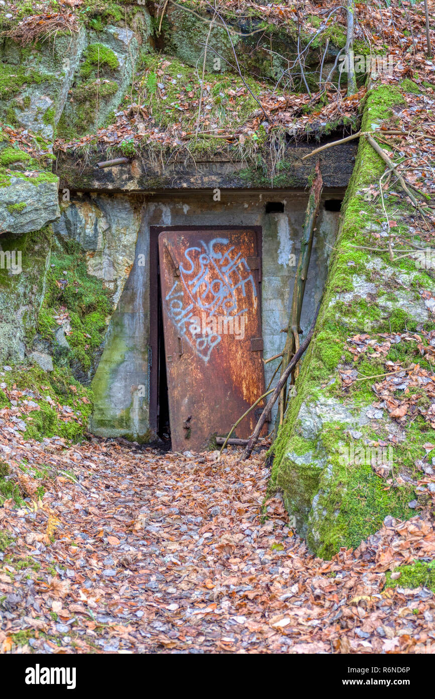 FLODA, SWEDEN - NOVEMBER 21 2018: Heavy metal door covered in graffiti slightly ajar leading into 1940s bomb shelter built into hill side and now decommissioned Stock Photo