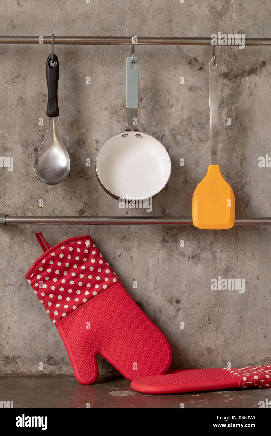 Kitchenware hanging on stainless rail on cement wall background Stock