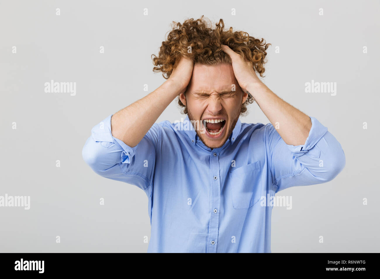 Portrait of a mad young man with curly hair isolated over white ...