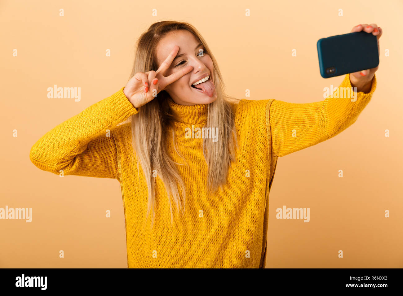 Portrait of a cheerful young woman dressed in sweater standing isolated ...