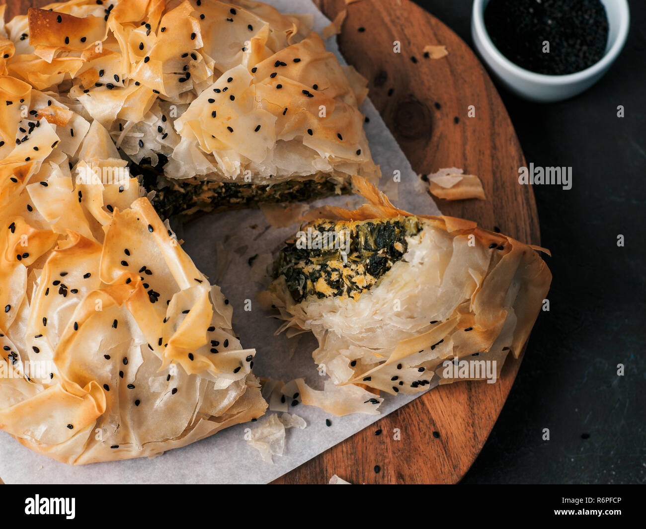 Greek pie spanakopita on dark background. Ideas and recipes for vegetarian or vegan Spanakopita Spinach Pie from fillo pastry cut in slices. Copy space. Top view or flat lay. Stock Photo