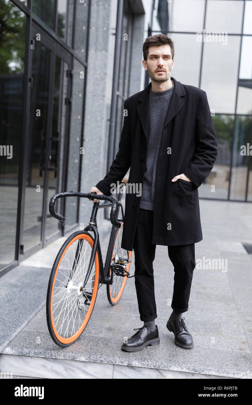 Image of handsome young business man walking outdoors with bicycle. Stock Photo