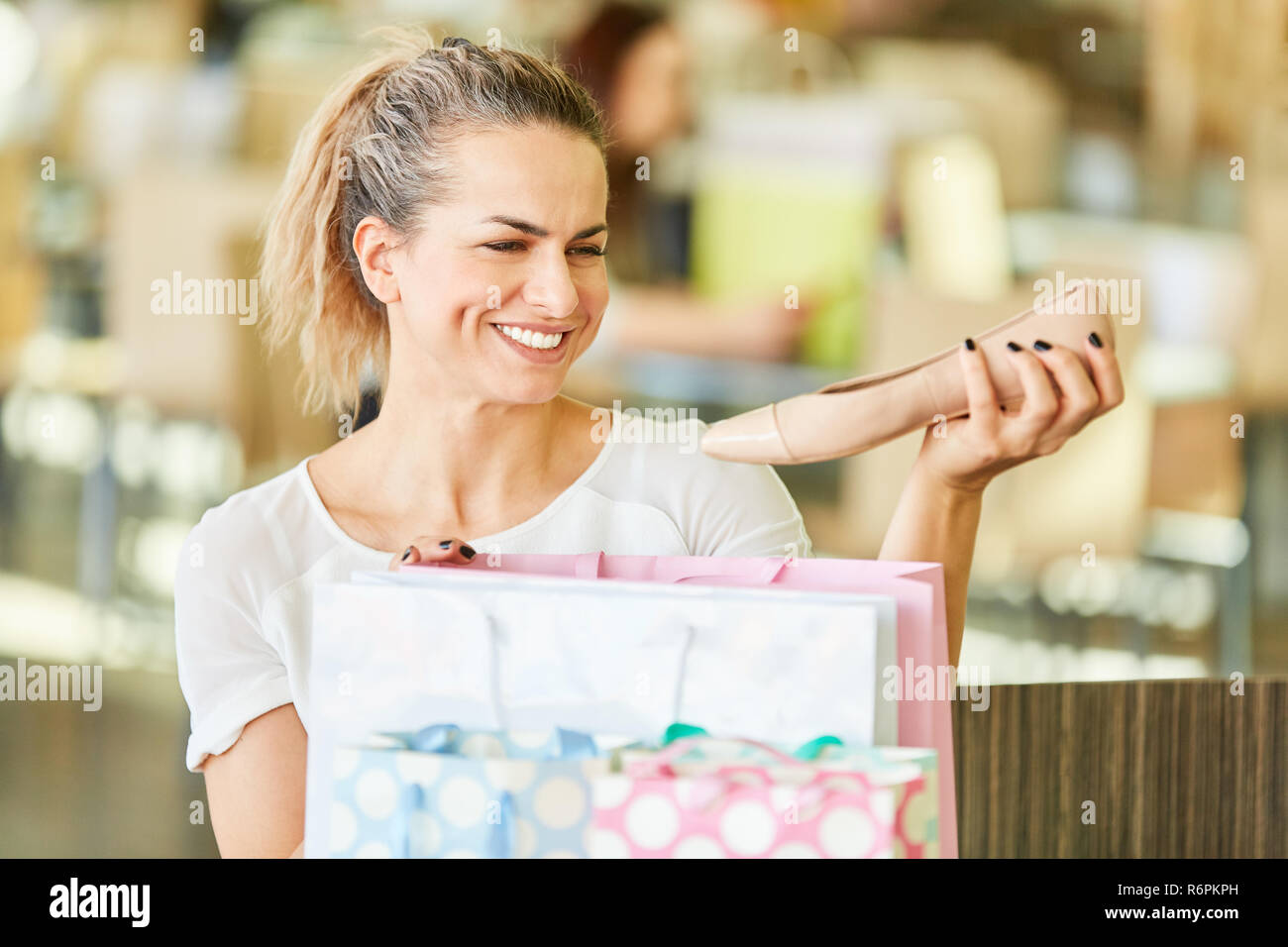 Young woman as a consumer is happy about new shoes while shopping Stock Photo