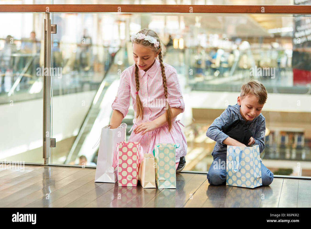 Two children in the shopping center unpack their shopping bags after shopping Stock Photo