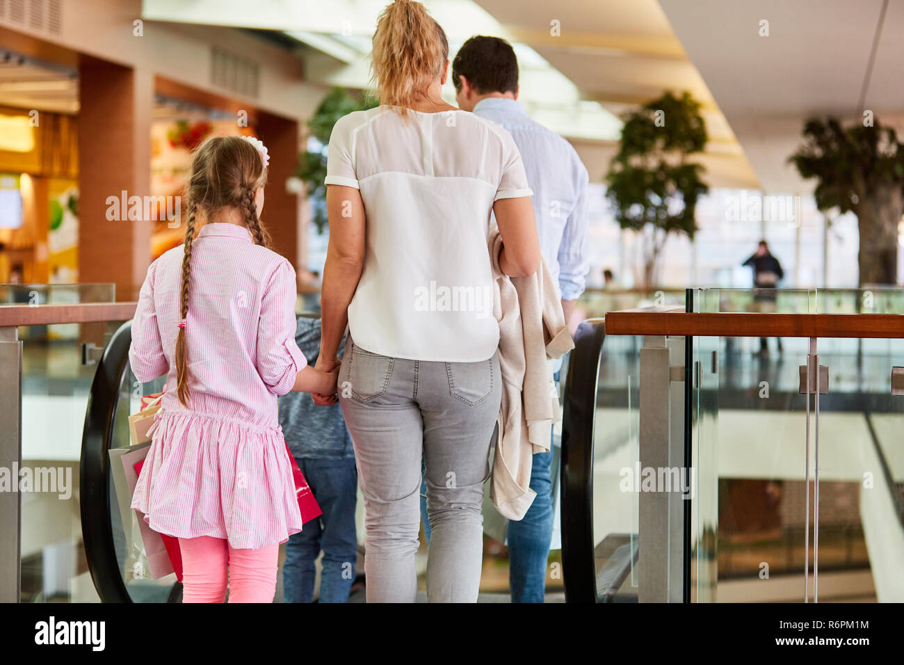 Family and children ride together escalator in shopping mall Stock Photo