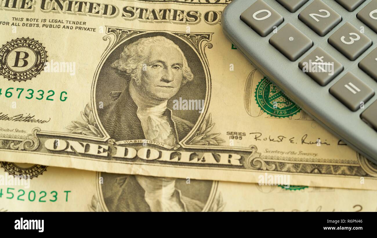 dollar banknotes and a calculator are lying on a table Stock Photo