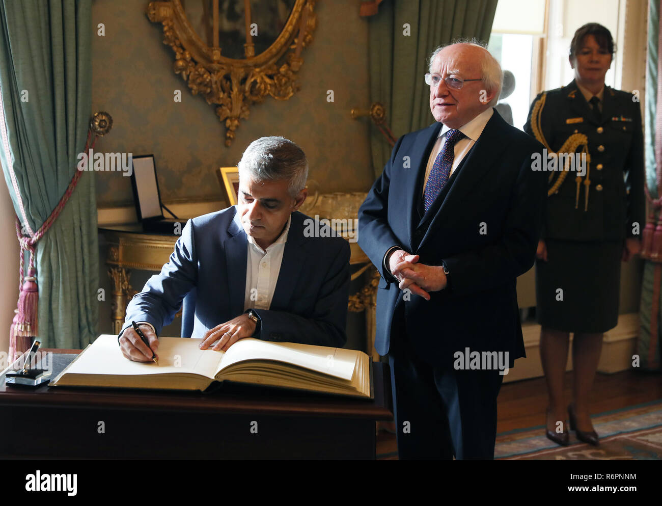 London Mayor Sadiq Khan (left) signs the visitor book alongside President Michael D Higgins at