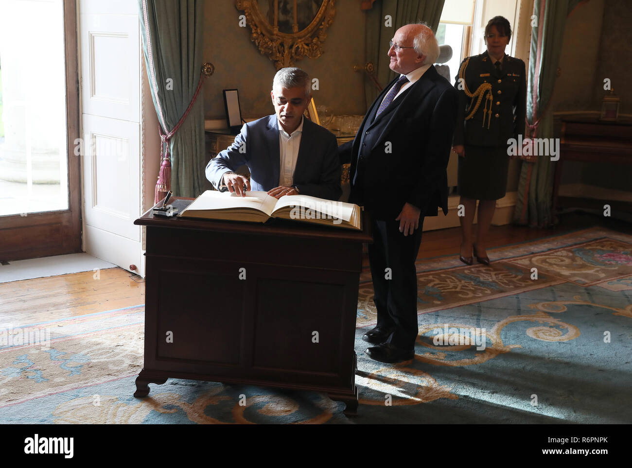 London Mayor Sadiq Khan (left) signs the visitor book alongside President Michael D Higgins at