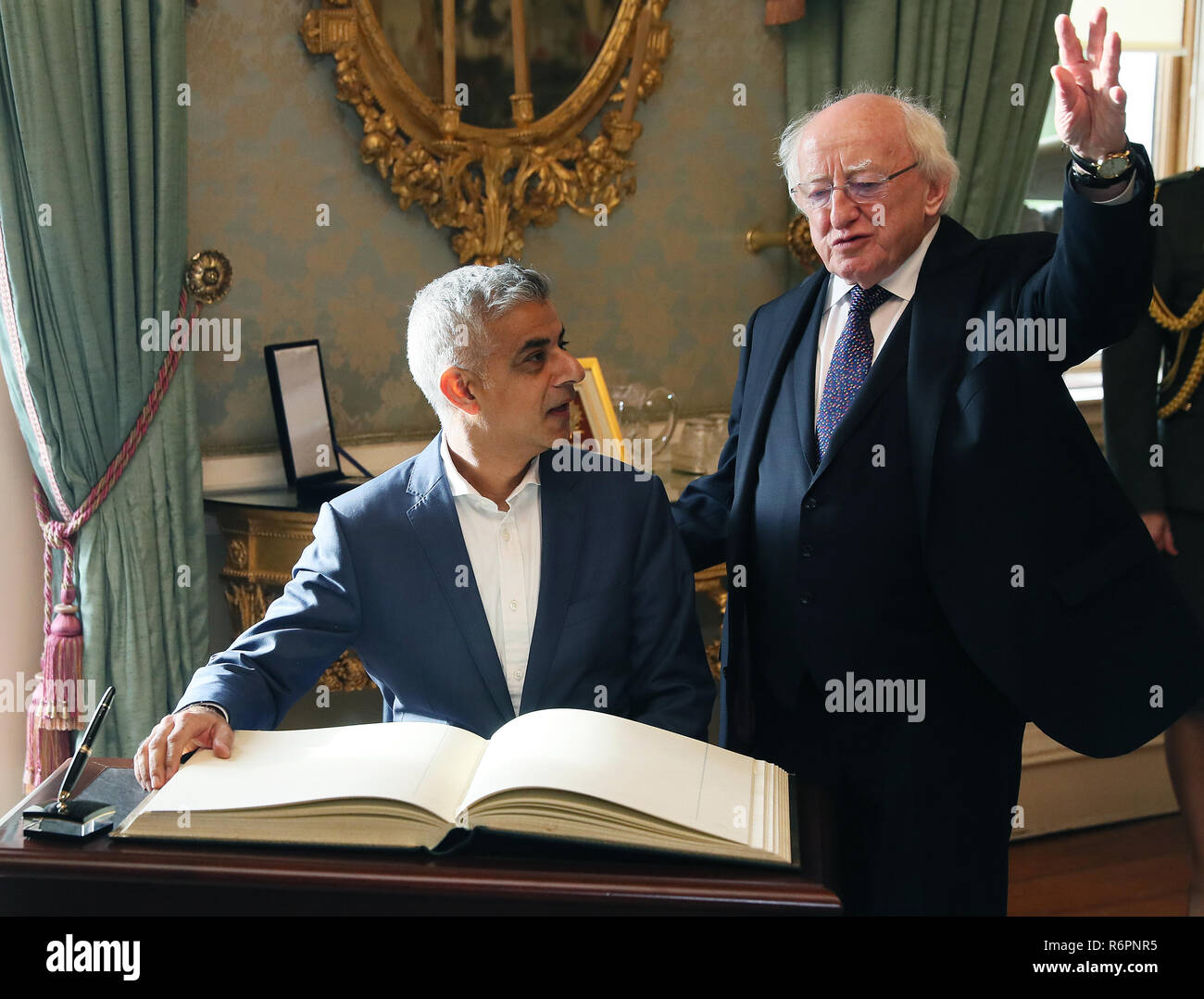 London Mayor Sadiq Khan (left) signs the visitor book alongside President Michael D Higgins at