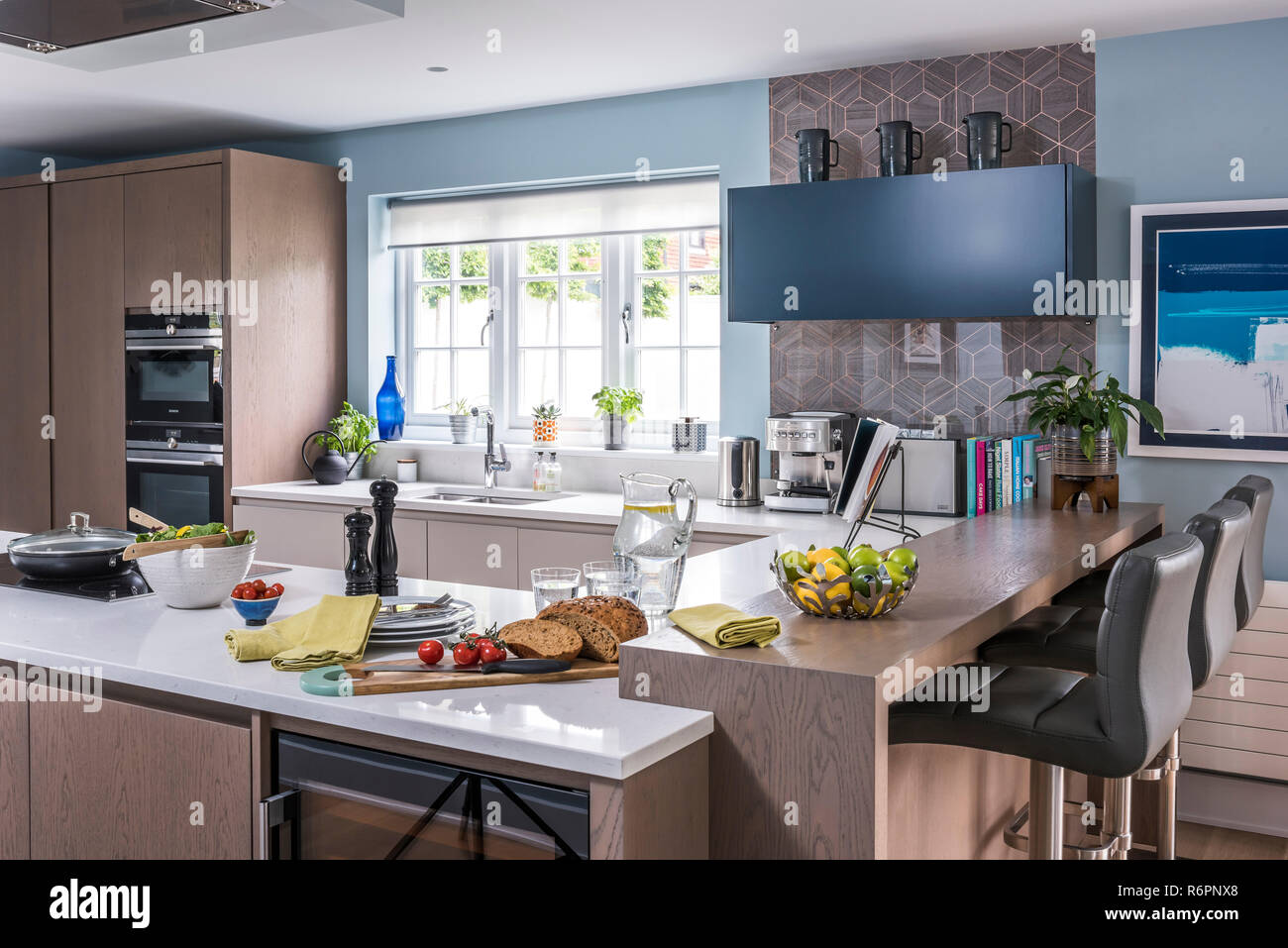 Grey barstools and wall mounted shelving with cut bread in kitchen of Hampshire Mill house redesigned by Emma Painter Stock Photo