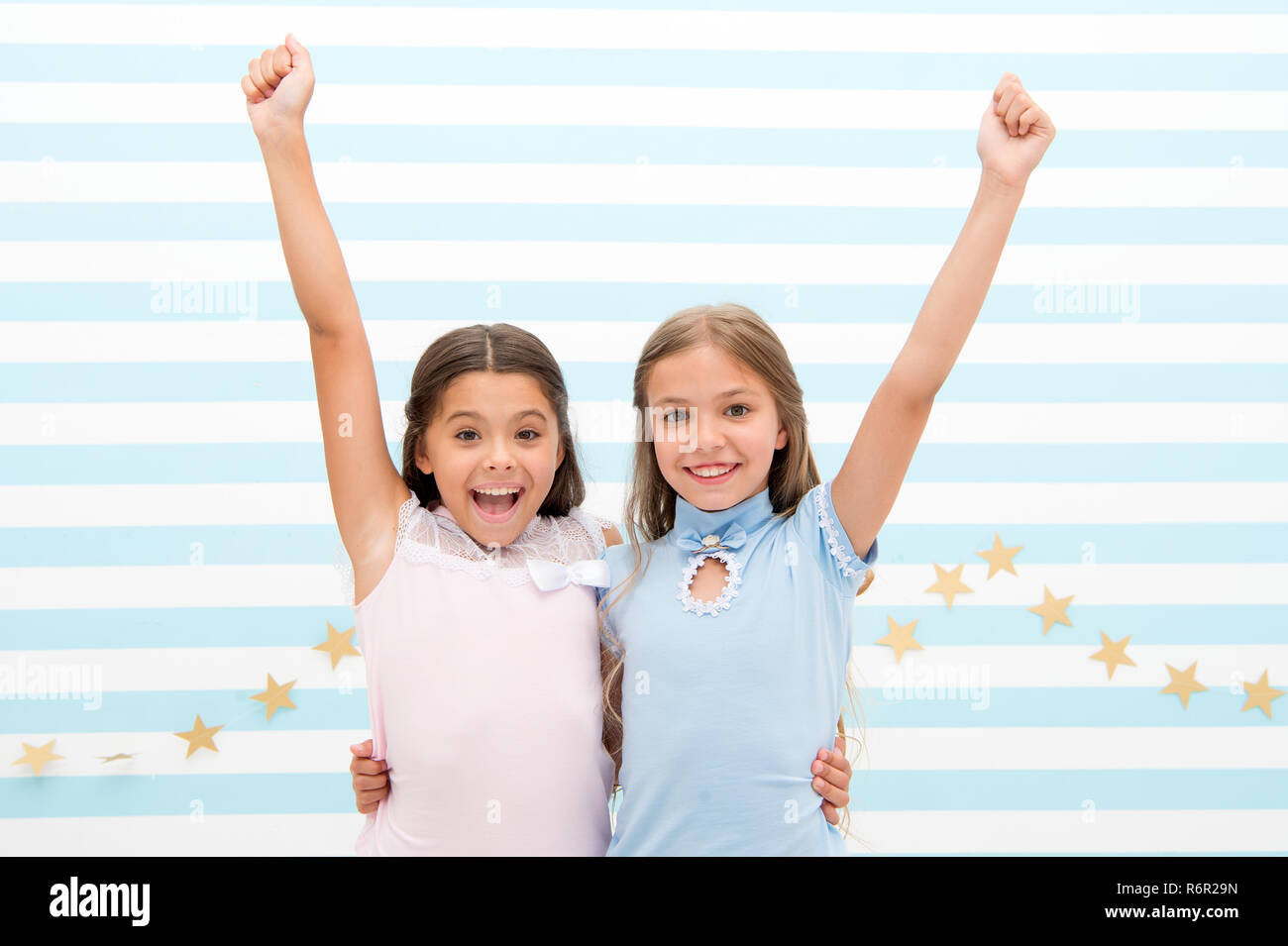 Live happy moments together. Kids schoolgirls preteens happy together. Friendship from childhood. Girls smiling happy faces hug each other stand striped background. Girls children best friends hug. Stock Photo