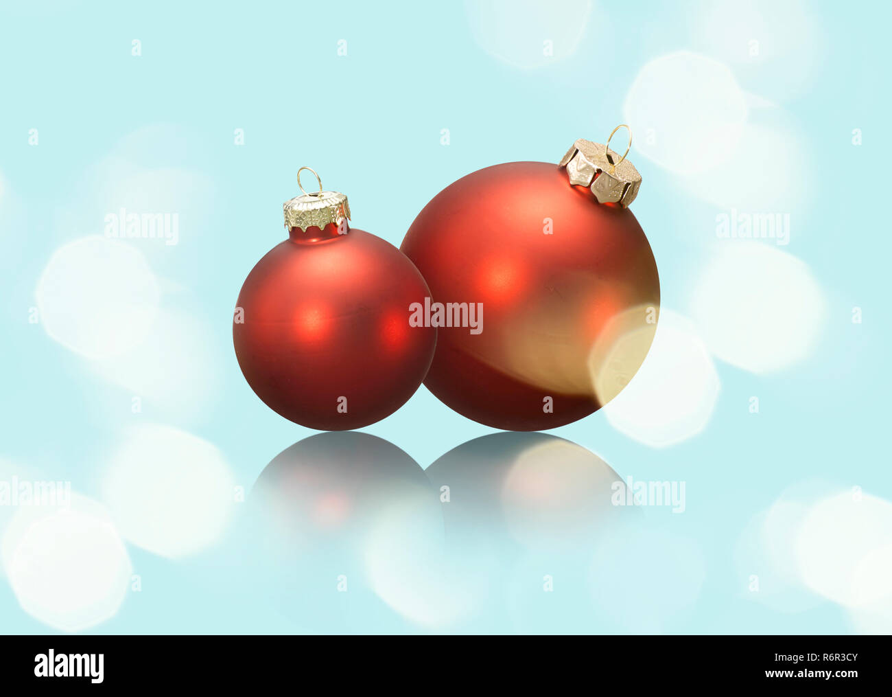 Zwei rote Weihnachtskugeln auf hellblauem Grund mit Spiegelung. Stock Photo