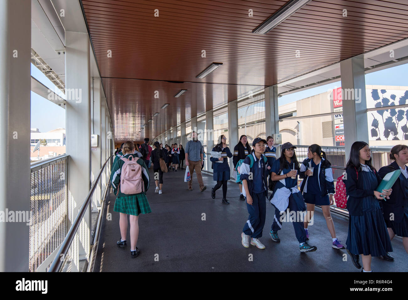 School children use the all weather pedestrian bridge that joins Hornsby railway station and shopping precinct, safely avoiding busy George St below. Stock Photo