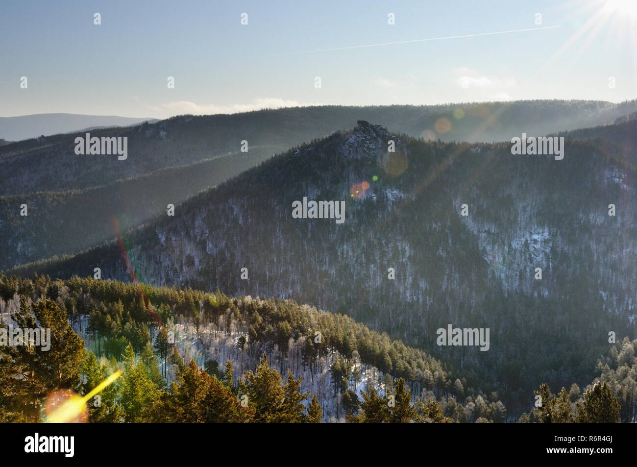 Winter mountain landscape with snowy mountains covered with pine tree forest during sunset in Stolby Nature Sanctuary at Krasnoyarsk, Russia Stock Photo
