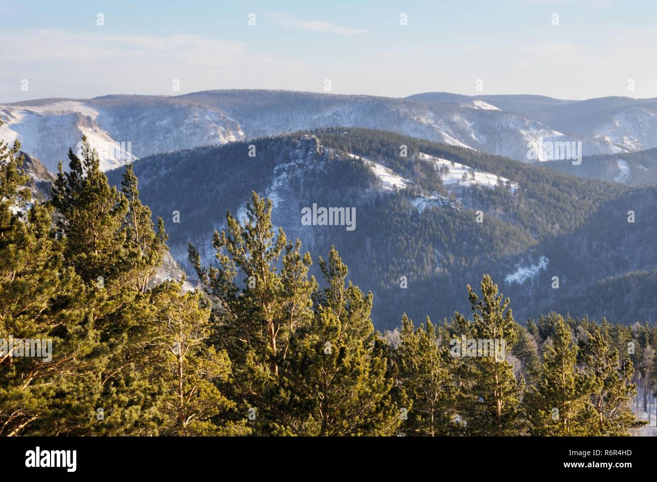 Winter mountain landscape with snowy mountains covered with pine tree forest during sunset in Stolby Nature Sanctuary at Krasnoyarsk, Russia Stock Photo