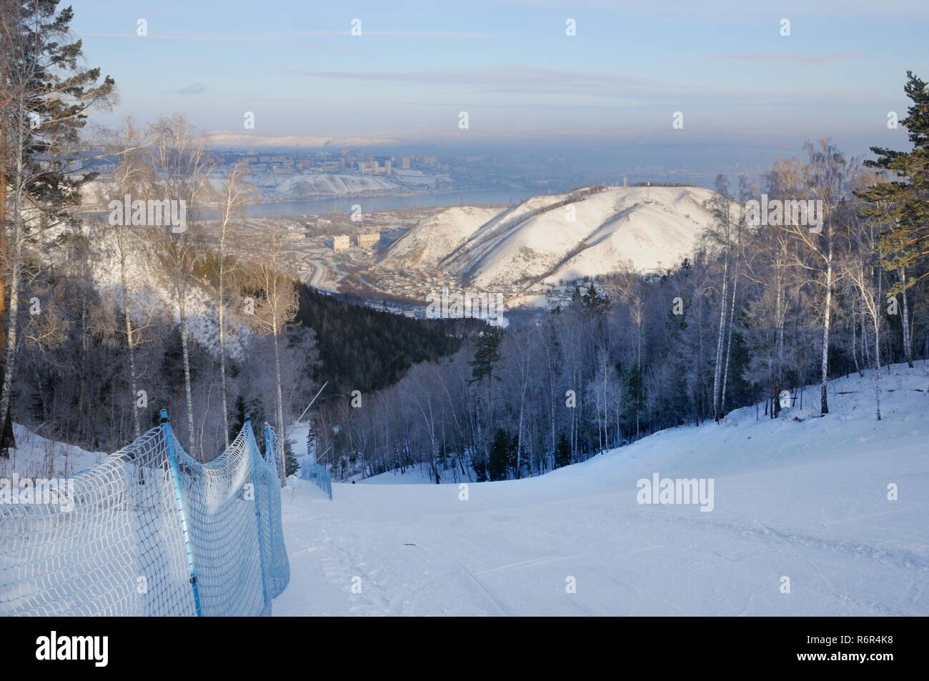 Winter landscape with a ski slope and a view of the city of Krasnoyarsk on the horizon in Siberia, Russia Stock Photo