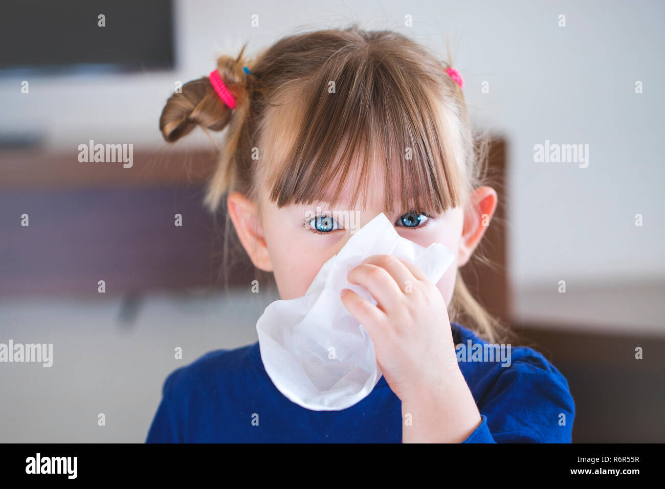 little girl blowing her nose into a handkerchief. Stock Photo