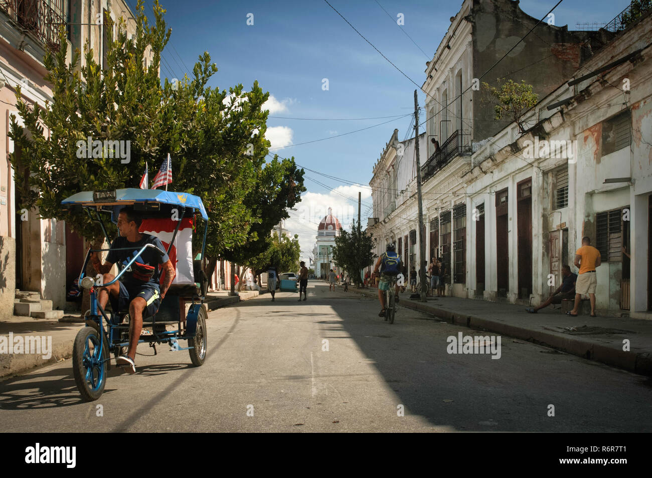 Streetview with a bicycle taxi waiting, and the old townhall in the background. Cienfuegos, Cuba. Stock Photo