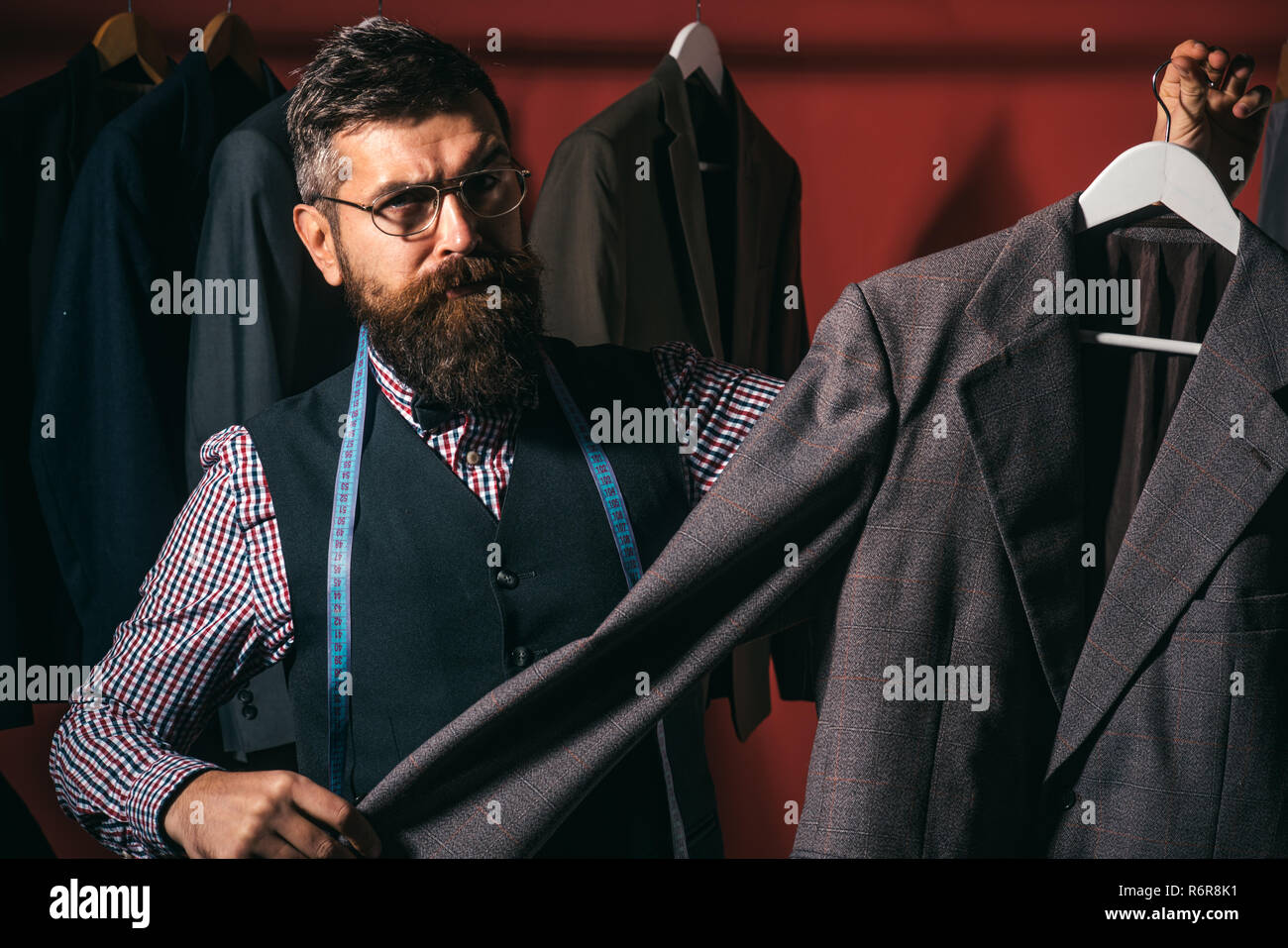 I have exactly what you are looking for. business dress code. Handmade.  suit store and fashion showroom. retro and modern tailoring workshop.  sewing mechanization. Bearded man tailor sewing jacket Stock Photo -