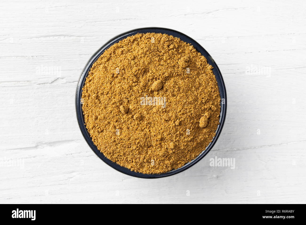 Caraway powder in round bowl on white wooden background, view directly from above. Stock Photo