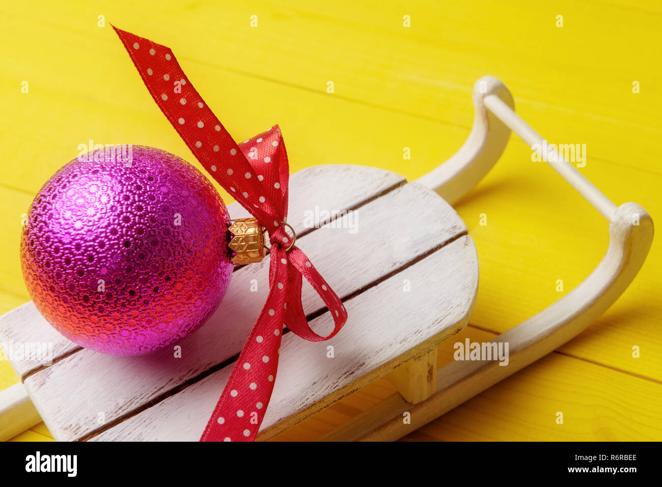 Pink Christmas ball with spotty ribbon on Santa's sleigh. Stock Photo
