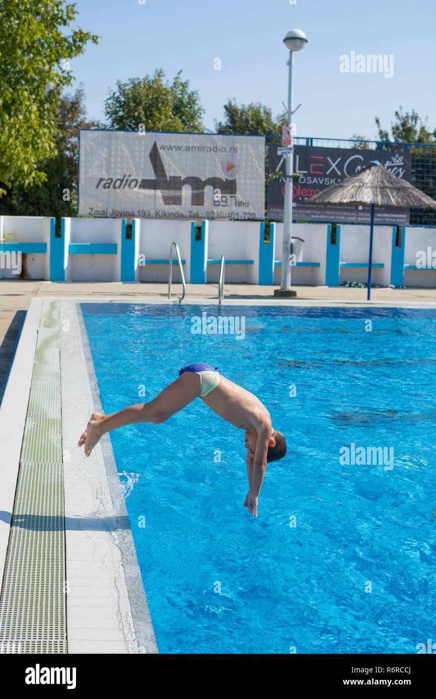 Seven year old boy doing swimming pool dive stop action shot Stock Photo