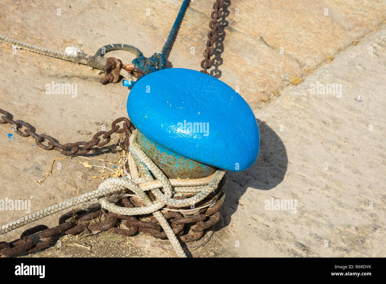 mooring rope of a little ship in the port. Mooring rope and bollard on sea water Stock Photo